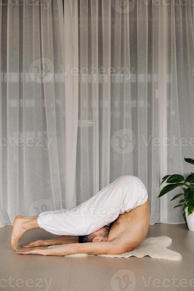 ein Mann mit ein nackt Torso tut Yoga im ein Fitness Zimmer. das Konzept von ein gesund Lebensstil foto