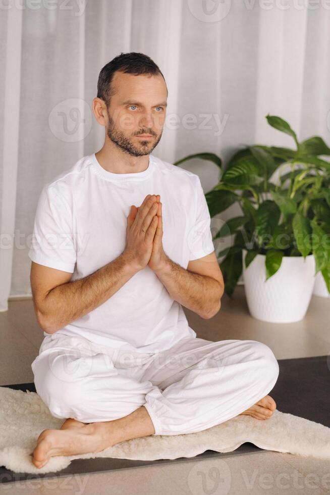 ein Mann im Weiß Sportbekleidung ist tun Yoga mit ein Fitness Zimmer. das Konzept von ein gesund Lebensstil foto