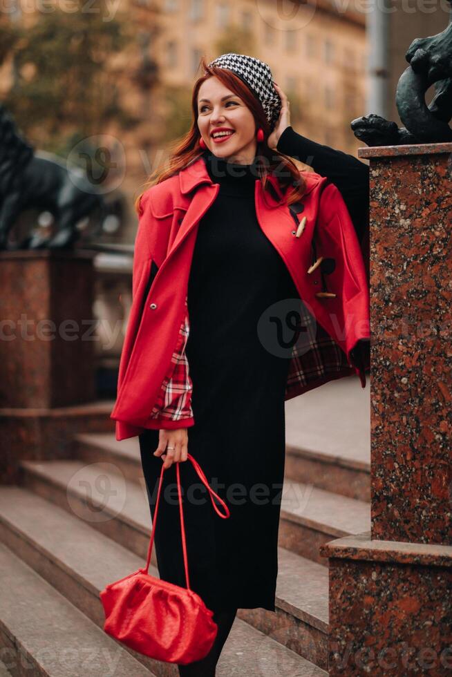 ein schön stilvoll Frau gekleidet im ein elegant rot Mantel mit ein stilvoll rot Handtasche im das Herbst Stadt foto