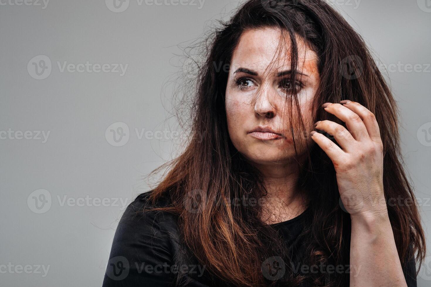 ein angeschlagen Frau im schwarz Kleider auf ein isoliert grau Hintergrund. Gewalt gegen Frauen foto
