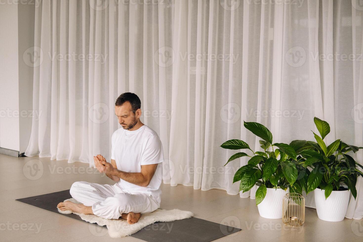 ein Mann im Weiß Sportbekleidung ist tun Yoga mit ein Fitness Zimmer. das Konzept von ein gesund Lebensstil foto