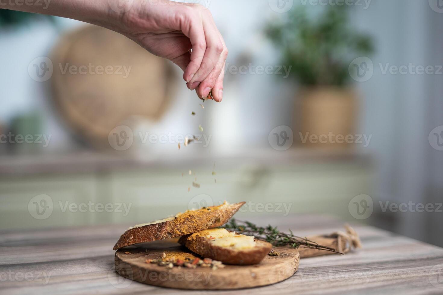 gießen Würze auf ein Sandwich mit Butter auf ein hölzern Tafel foto