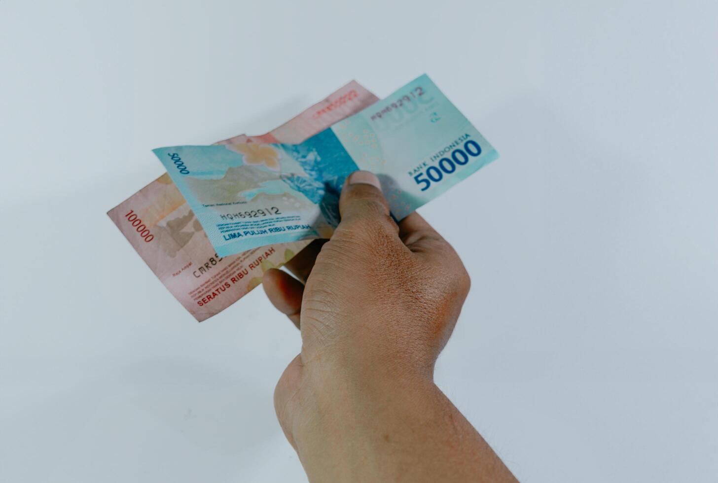 indonesisch Währung. Hand halten 100.000 und 50.000 Rupiah Banknoten auf ein Weiß Hintergrund. foto