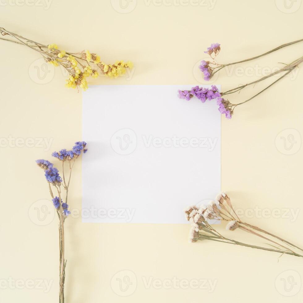 kreativ Layout gemacht von bunt trocken Blumen mit Papier Karte Hinweis auf Pastell- Sahne Hintergrund. Blumen- Gruß Karte. minimal Konzept und Einfachheit. Natur dekorativ Design. eben legen. foto