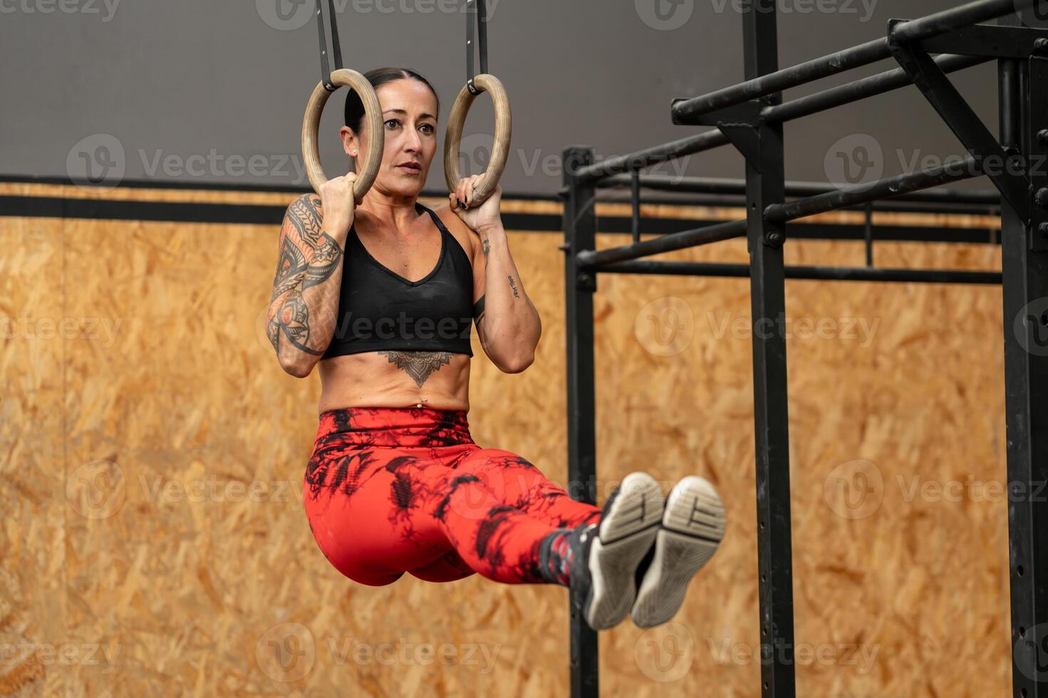 Frau durchführen Ader Übungen hängend von olympisch Ringe foto
