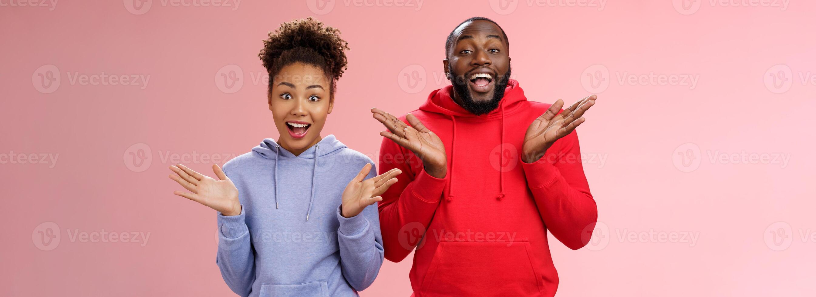 beeindruckt glücklich begeistert jung Paar afrikanisch Mann Frau Beziehung klatschen Palmen freudig überrascht breit Augen freudig Gruß freunde einladend Kommen Sie im gastfreundlich, Stehen Rosa Hintergrund foto