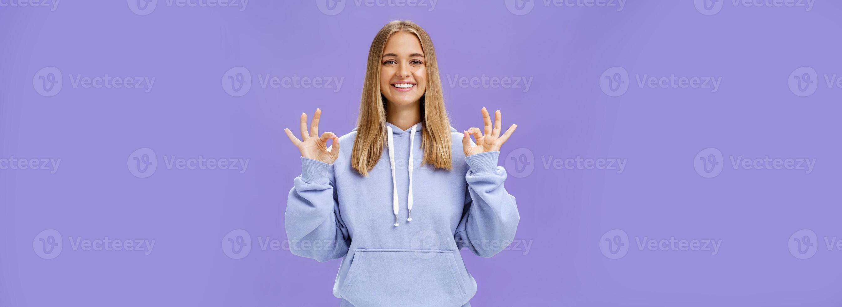 Mädchen habe alles unter Kontrolle. Erfreut glücklich charmant Frau mit Messe Haar und Braun gebrannt Haut ohne bilden zeigen okay Geste lächelnd versicherte und zufrieden posieren im Kapuzenpullover Über lila Mauer foto