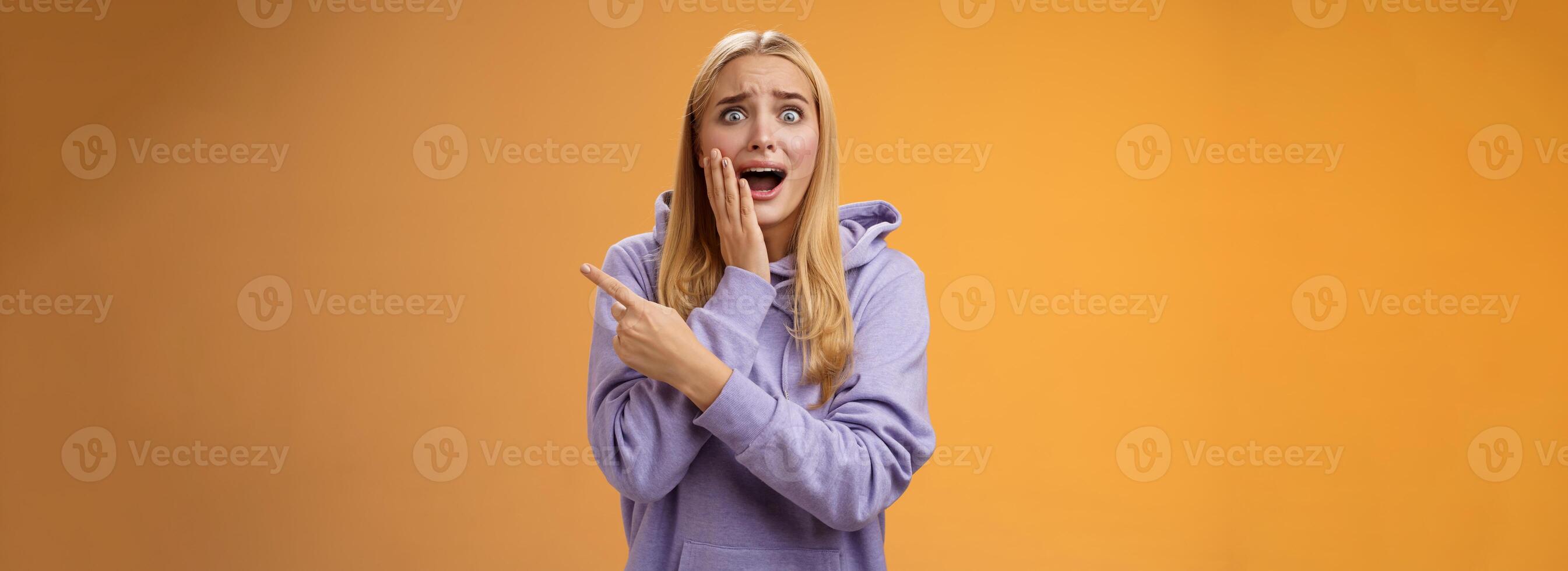 erstaunt aufgeregt überwältigt jung blond Mädchen im Kapuzenpullover Drücken Sie Palme Wange schreiend erstaunt zeigen richtig Sehen berühmt Super Star kann nicht halt froh positiv Emotionen, Orange Hintergrund foto