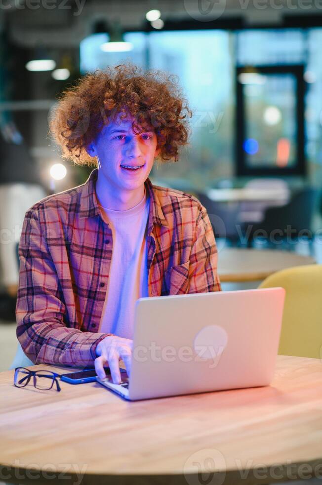 heiter männlich Freiberufler Surfen komisch Video Inhalt während Vernetzung im Sozial Medien mit Netbook Technologie im Straße Cafe, glücklich Hipster Kerl genießen kostenlos Zeit zum online Bloggen über Laptop foto