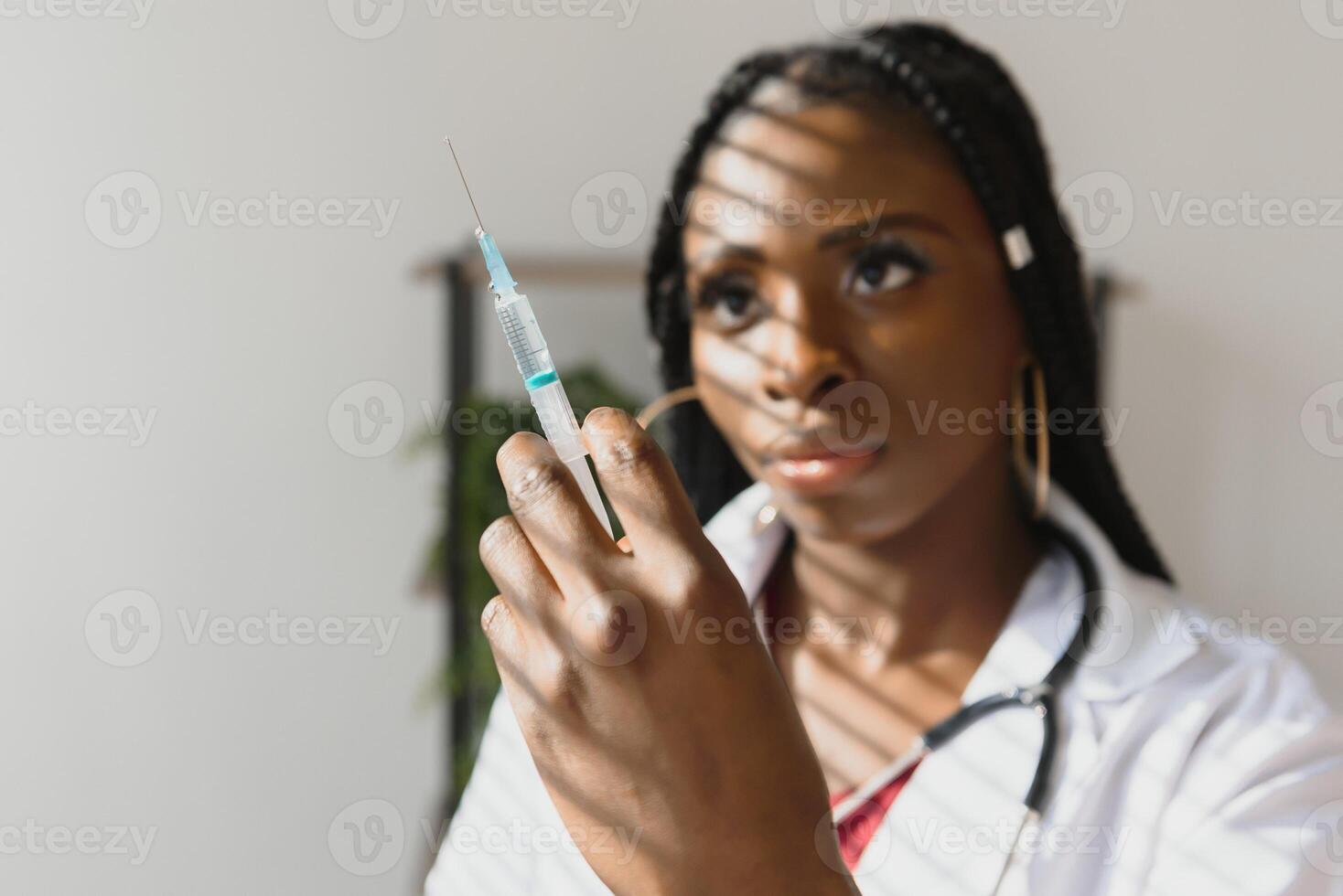 Vorderseite Aussicht von jung Afroamerikaner weiblich Arzt halten Spritze mit Nadel bereit zu injizieren beim das Krankenhaus. foto