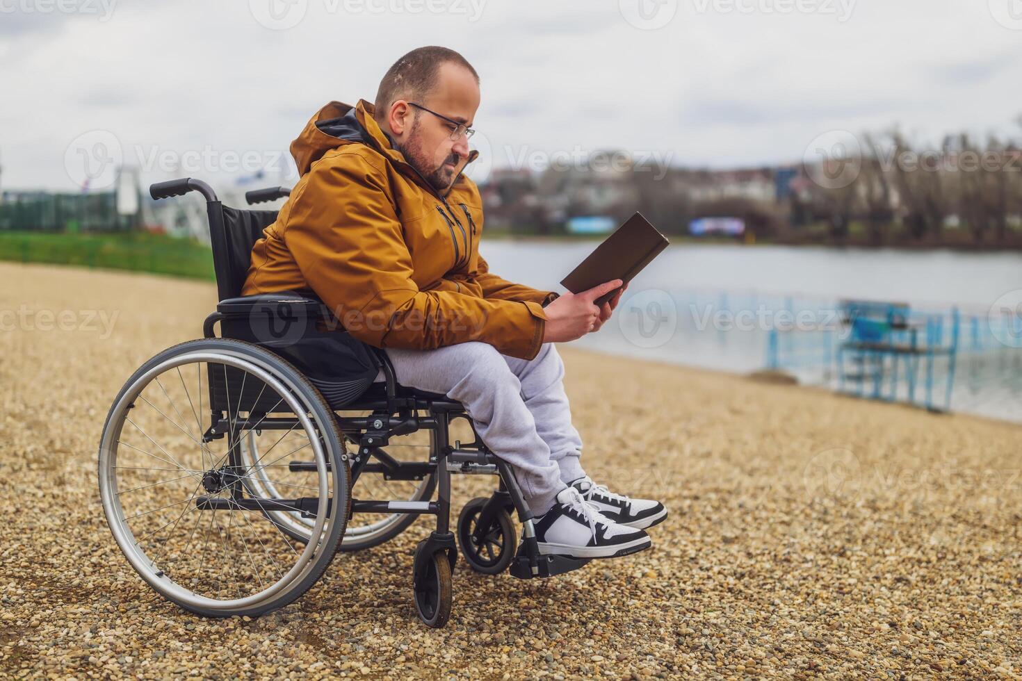 Paraplegiker behindert Mann im Rollstuhl ist lesen Buch draussen. foto