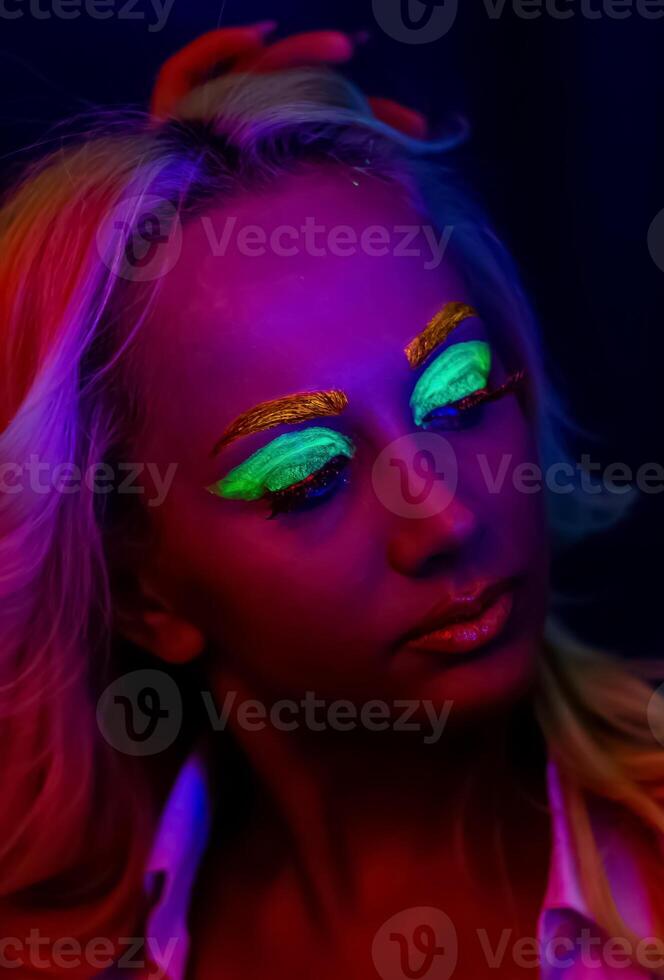 Porträt von ein Frau mit gemalt Gesicht, Frau mit uv bilden im Studio, Porträt von ein Frau im Karneval Maske, das Frau ist dekoriert im ein ultraviolett Pulver foto