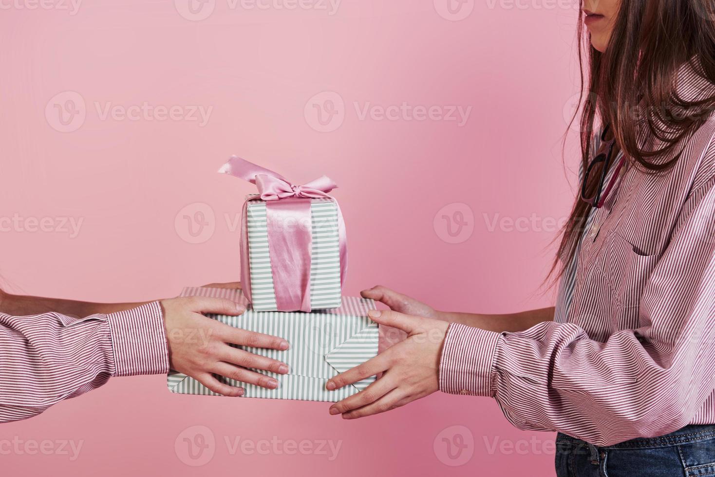 Nahaufnahme Foto von zwei Mädchen mit Geschenkboxen auf rosa Hintergrund im Studio