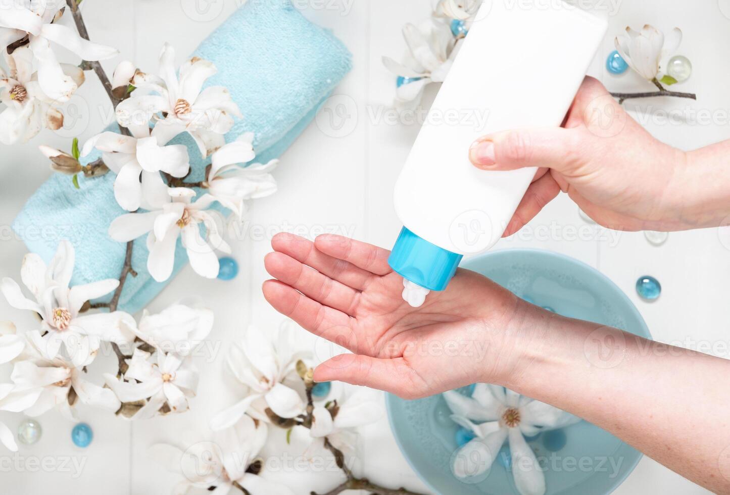 jung Frau tun Schritt durch Schritt Hand Massage mit Sahne im Salon mit Tasse von Frühling Wasser und Weiß Magnolie Blumen foto