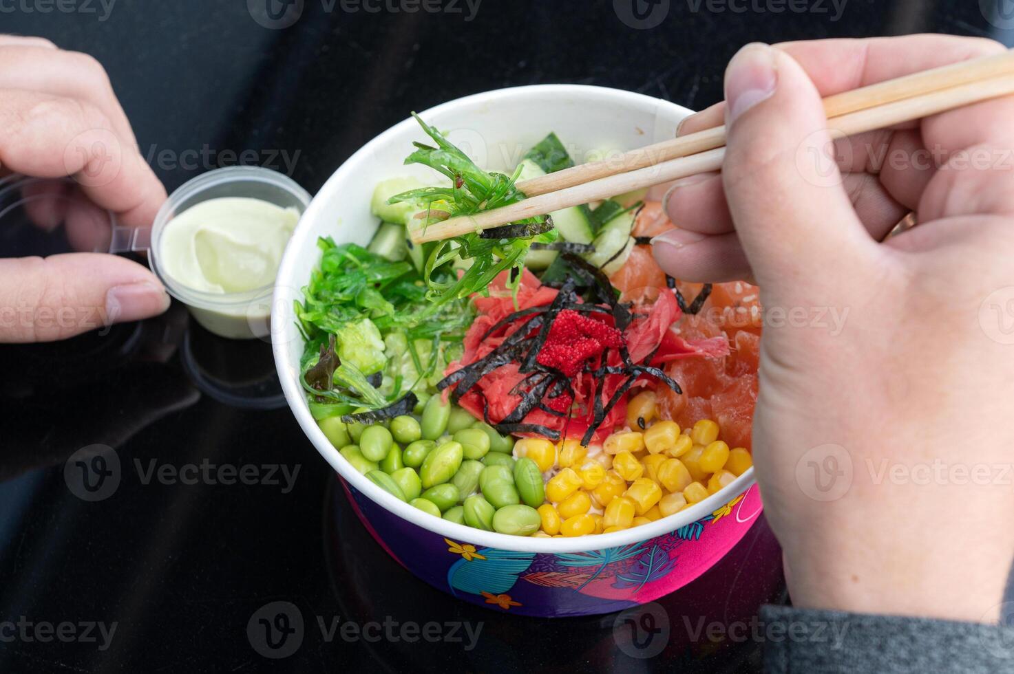 das Aufgabe im das Schüssel ist ein Salat von roh rot Fisch serviert wie ein Snack, hawaiisch Küche. des Mannes Hände foto