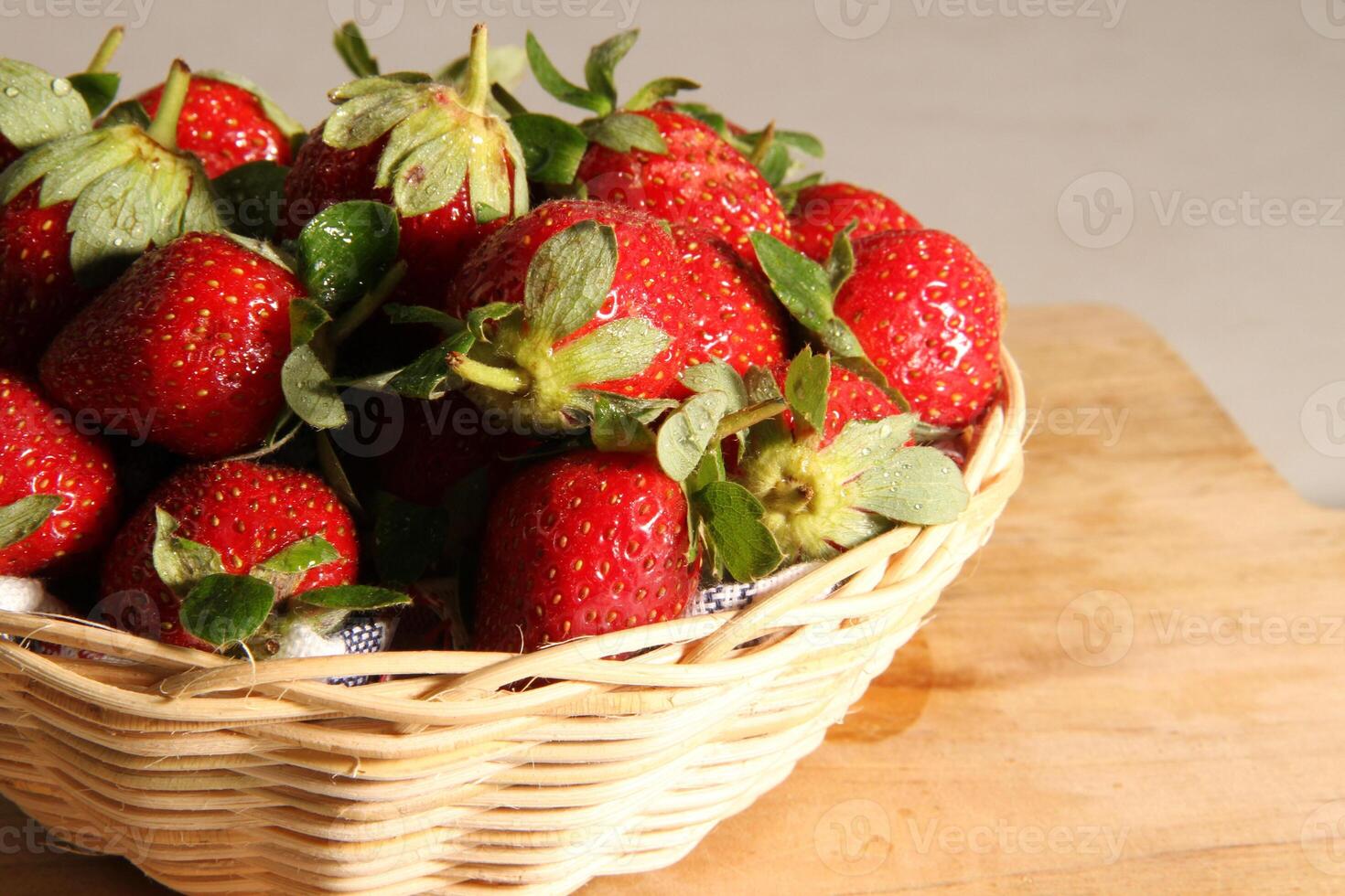 ein Korb von Erdbeeren auf ein hölzern Schnitt Tafel auf Weiß Hintergrund foto
