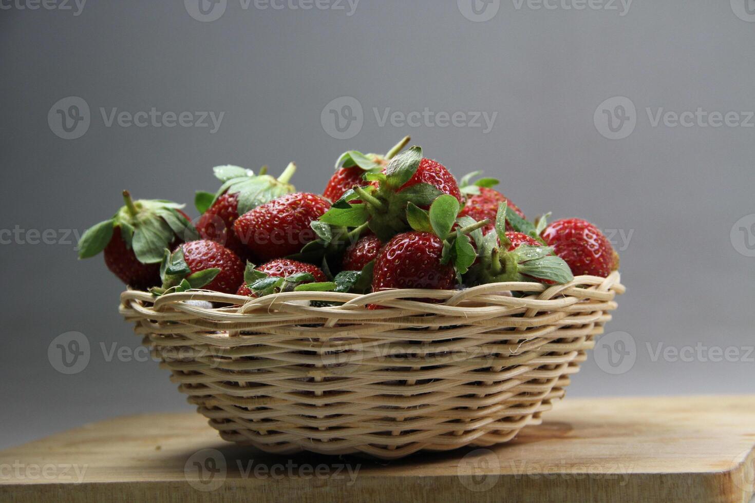 ein Korb von Erdbeeren auf ein hölzern Schnitt Tafel auf Weiß Hintergrund foto