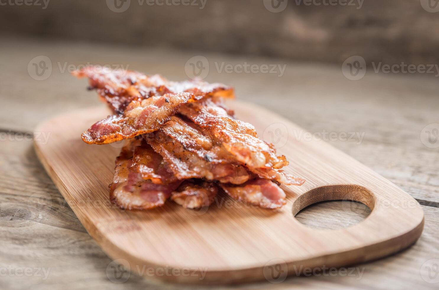 Stapel von gebraten Speck Streifen auf das hölzern Tafel foto