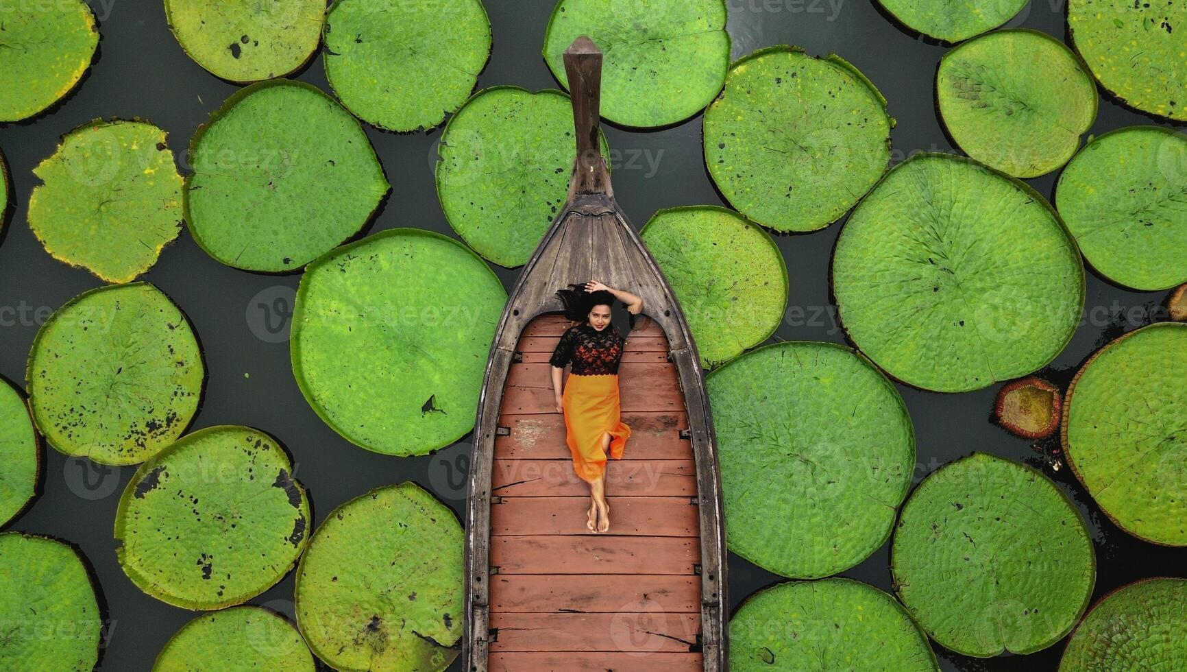 Antenne Aussicht von ein asiatisch Frau entspannend auf ein Boot draussen auf Lotus Teich beim Phuket Thailand foto