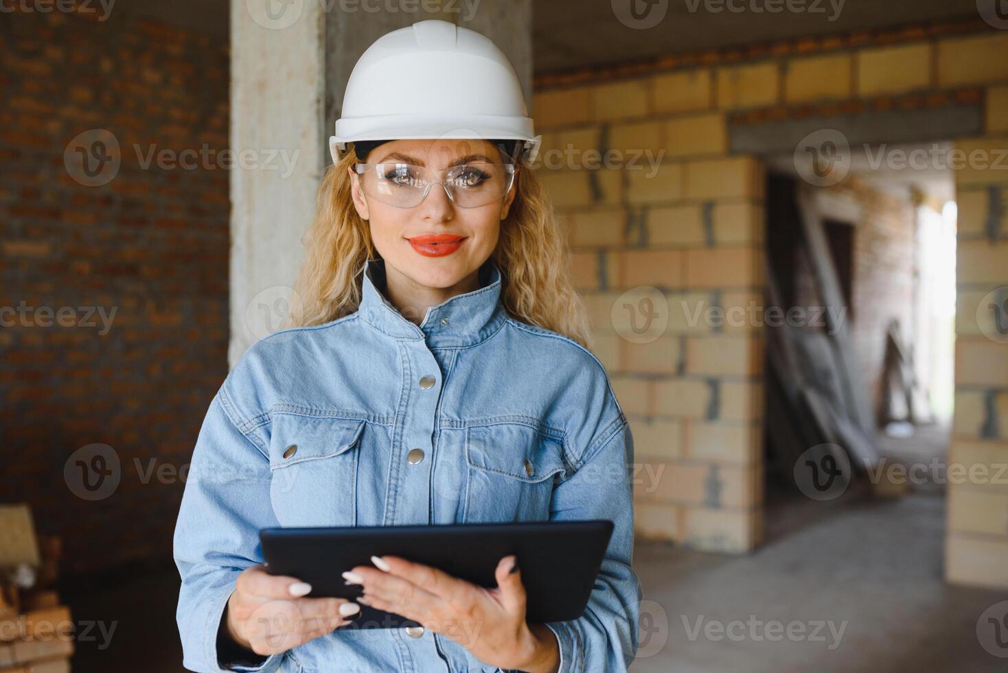 absorbiert im das Arbeit von ein Frau Ingenieur Arbeiten mit ein Tablette auf das Hintergrund von das Konstruktion Seite? ˅. Porträt von ein jung Architekt, schützend Ausrüstung. selektiv Fokus. foto