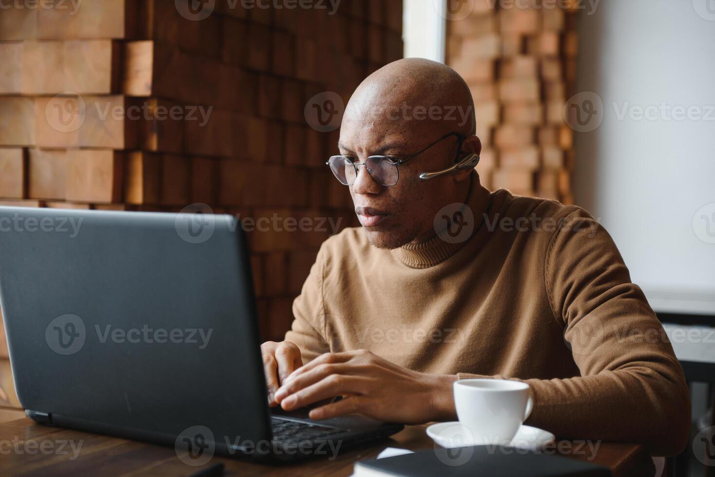 konzentriert afrikanisch Mann tragen Kopfhörer Aufpassen Webinar Ausbildung Herstellung Anmerkungen Studie online Lernen Sprache auf Computer, schwarz männlich Schüler suchen beim Laptop E-Learning im Internet schreiben Information. foto
