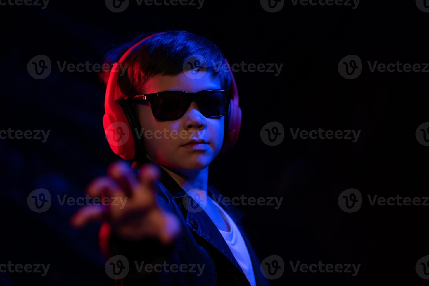 Teen Junge Hören zu Musik- mit Kopfhörer, Neon- Licht Trend Porträt. sieht aus beim das Kamera foto