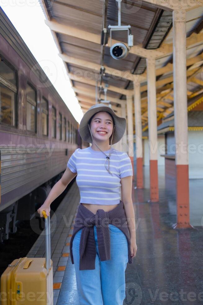 jung Frau mit Koffer wartet beim das Metro Bahnhof während das Zug kommt an, Tourismus und Reise im das Sommer. Urlaube zum das Student. Arbeit und Reise foto