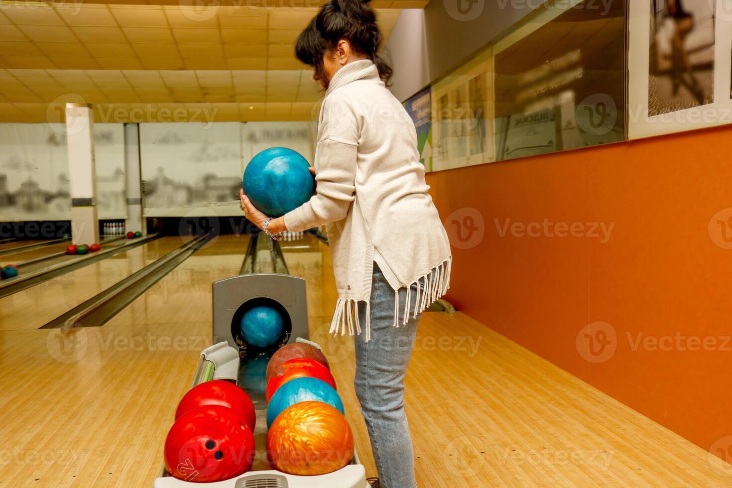 Senior Frau wählen ein Ball im ein Bowling Verein. foto