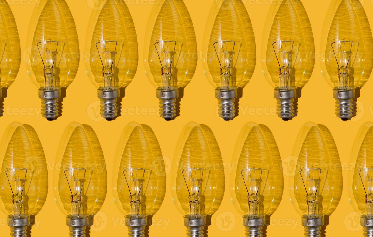 Gelb Hintergrund. elektrisch Licht Glühbirnen Muster. ein alt Glas elektrisch Licht Birne mit ein Wolfram Filament. das Konzept von Elektrizität Verbrauch und sparen. foto
