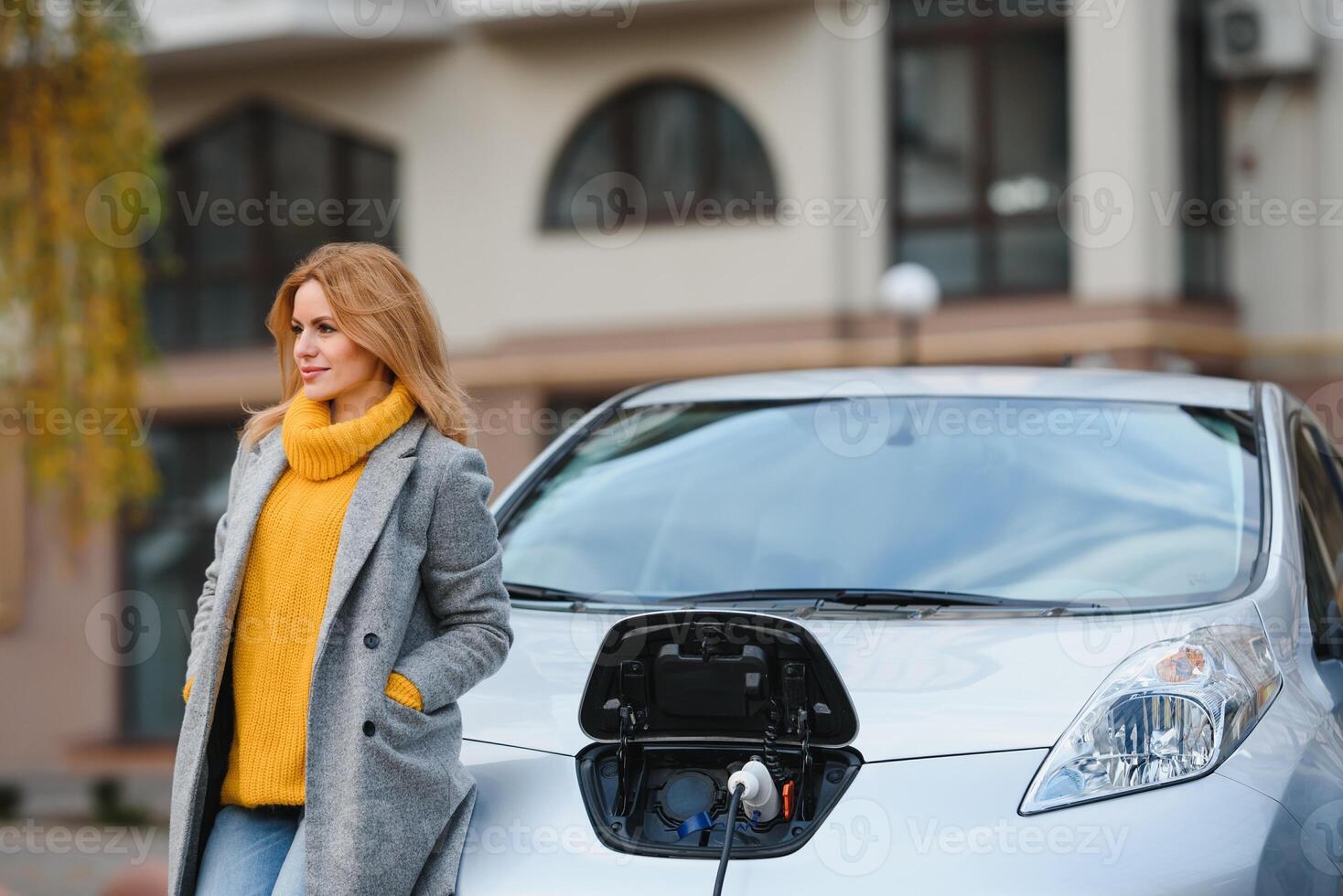 Frau in der Nähe von ein Vermietung elektrisch Wagen. Fahrzeug berechnet beim das Laden Bahnhof. foto