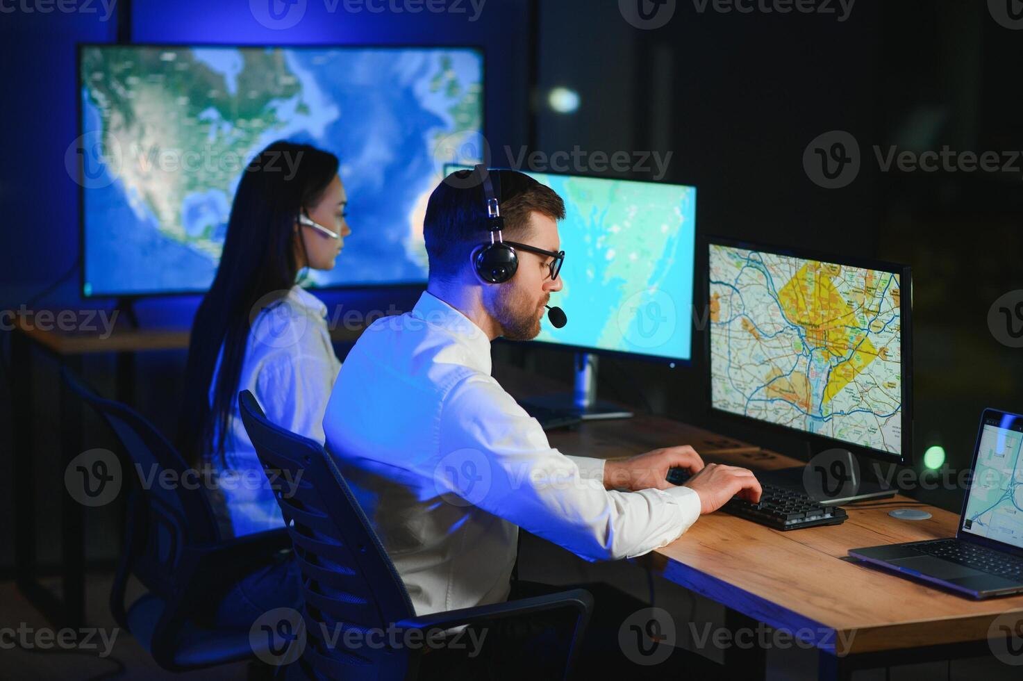 im Überwachung Zimmer technisch Unterstützung Spezialist spricht in Headset. seine Kollegen sind Arbeiten im das Hintergrund foto