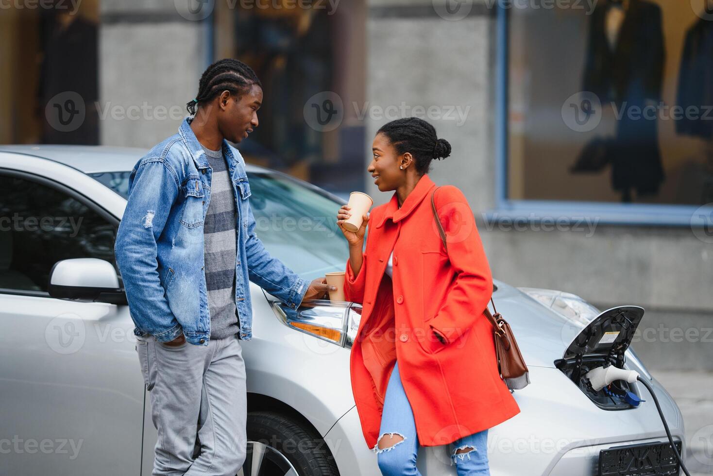 glücklich jung Erwachsene afrikanisch amerikanisch Mann und lächelnd Frau Laden elektrisch Wagen. foto