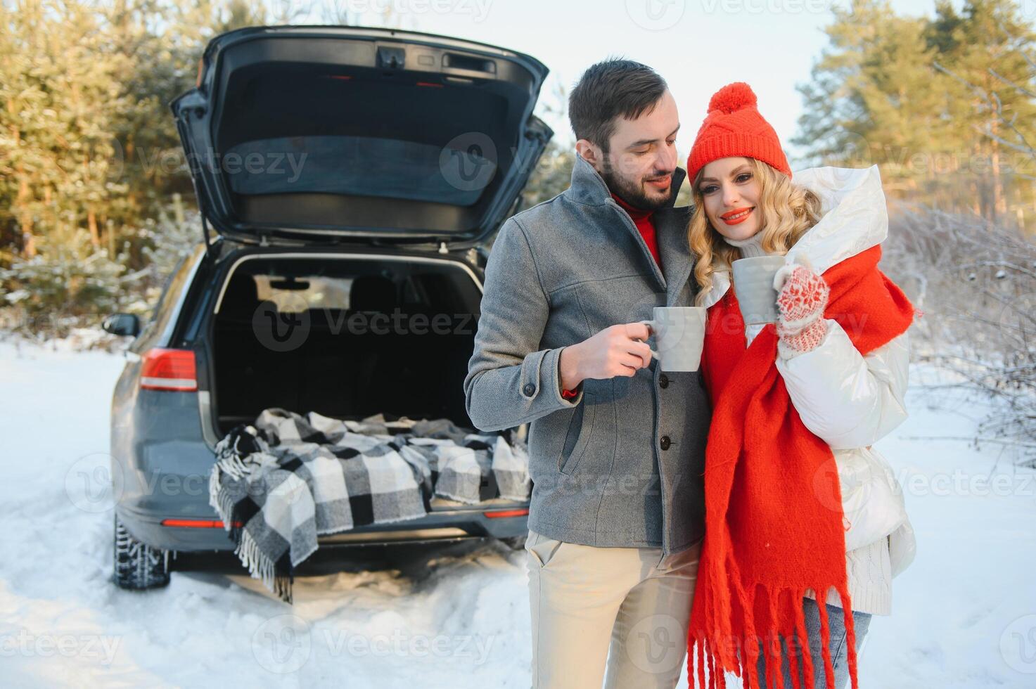 Paar im Liebe Sitzung im Auto Kofferraum Trinken heiß Tee im schneebedeckt Winter Wald und chatten. Menschen entspannend draußen während Straße Reise. Valentinsgrüße Tag foto