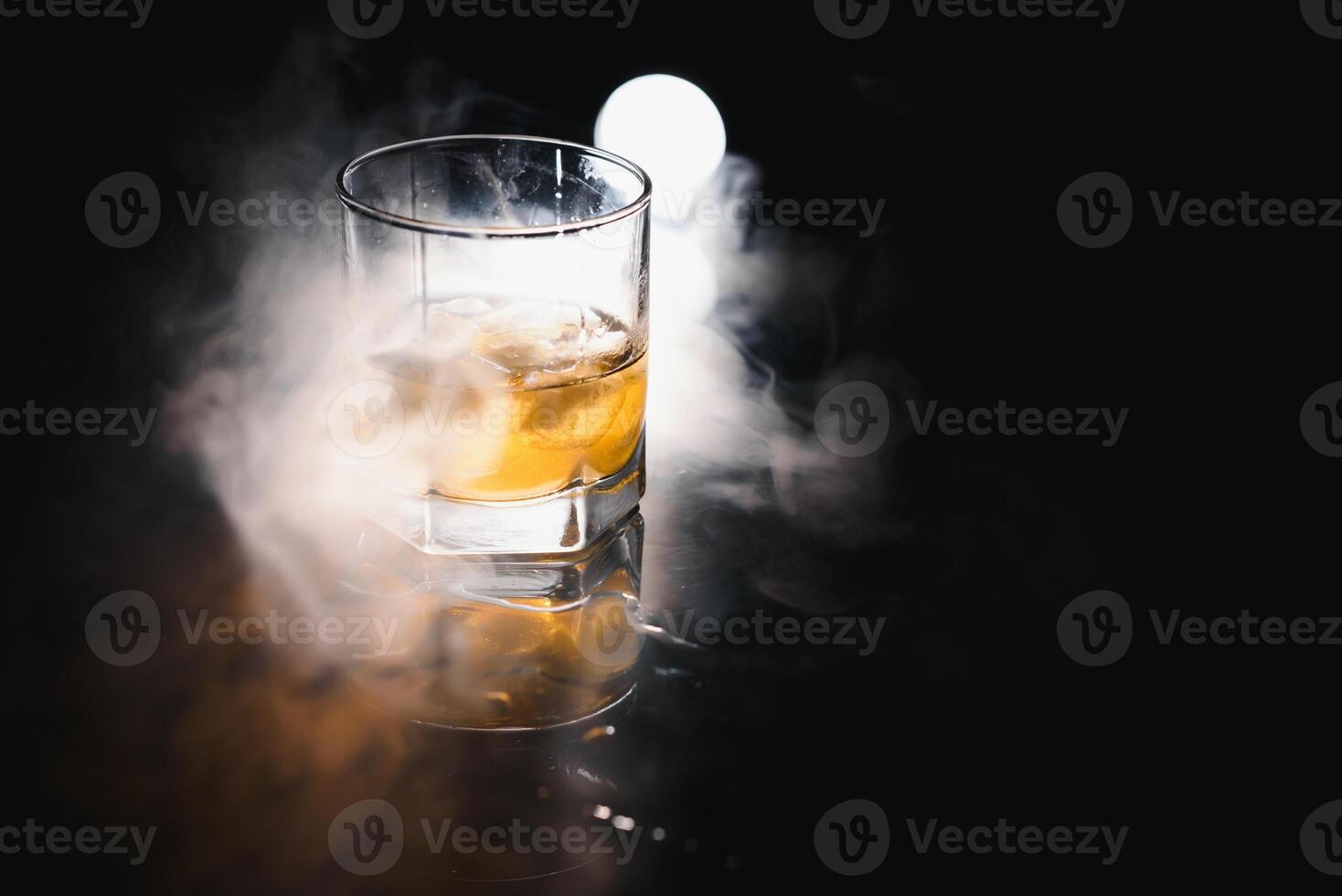 Whiskey mit Eis auf schwarz Hintergrund mit Rauch foto