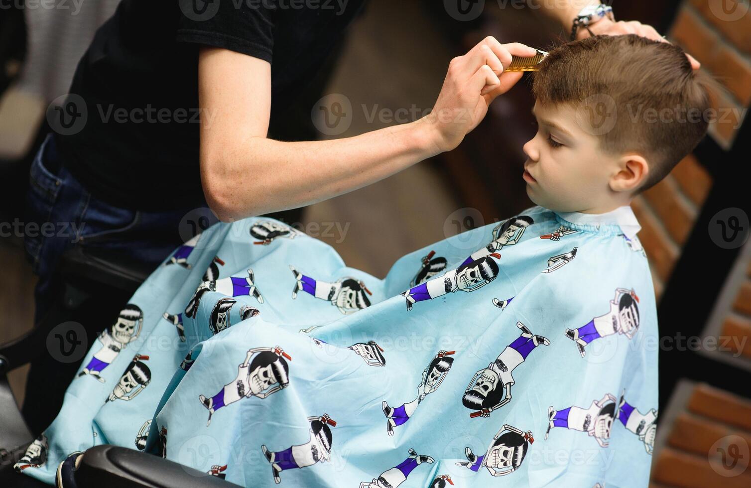 Seite Aussicht von süß wenig Junge bekommen Haarschnitt durch Friseur beim das Friseurladen. foto