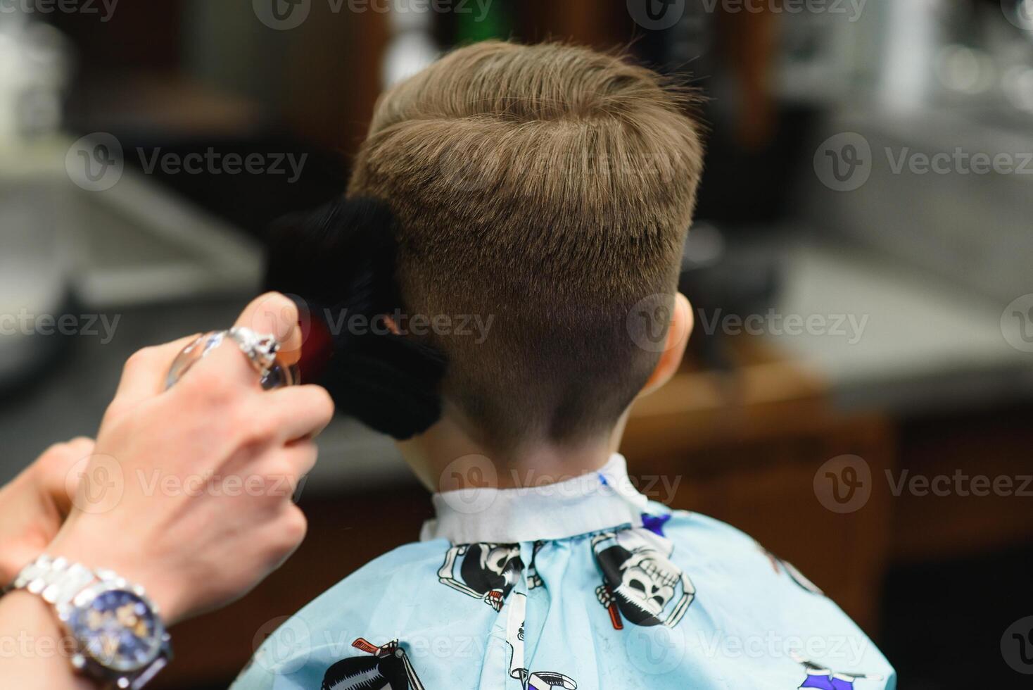 ein wenig süß Junge sitzt im ein Friseur beim das Stylisten, ein Schulkind ist bekommen Haar Schnitt im ein Schönheit Salon, ein Kind beim ein Friseursalons, ein kurz Herren Haarschnitt foto