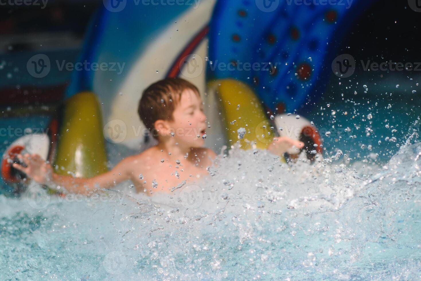 das Junge ist rollen mit ein Wasser rutschen beim ein Wasser Park im wenig Felsen foto