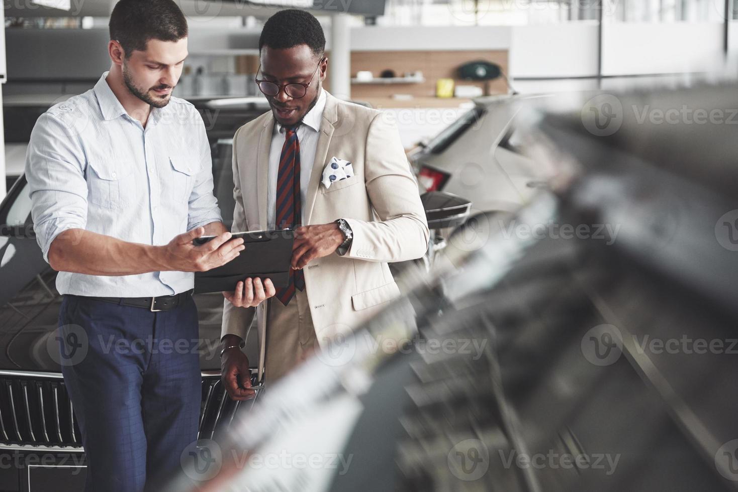 Eine junge schwarze Geschäftsfrau unterschreibt Dokumente und kauft ein neues Auto. der Autohändler steht neben ihm foto