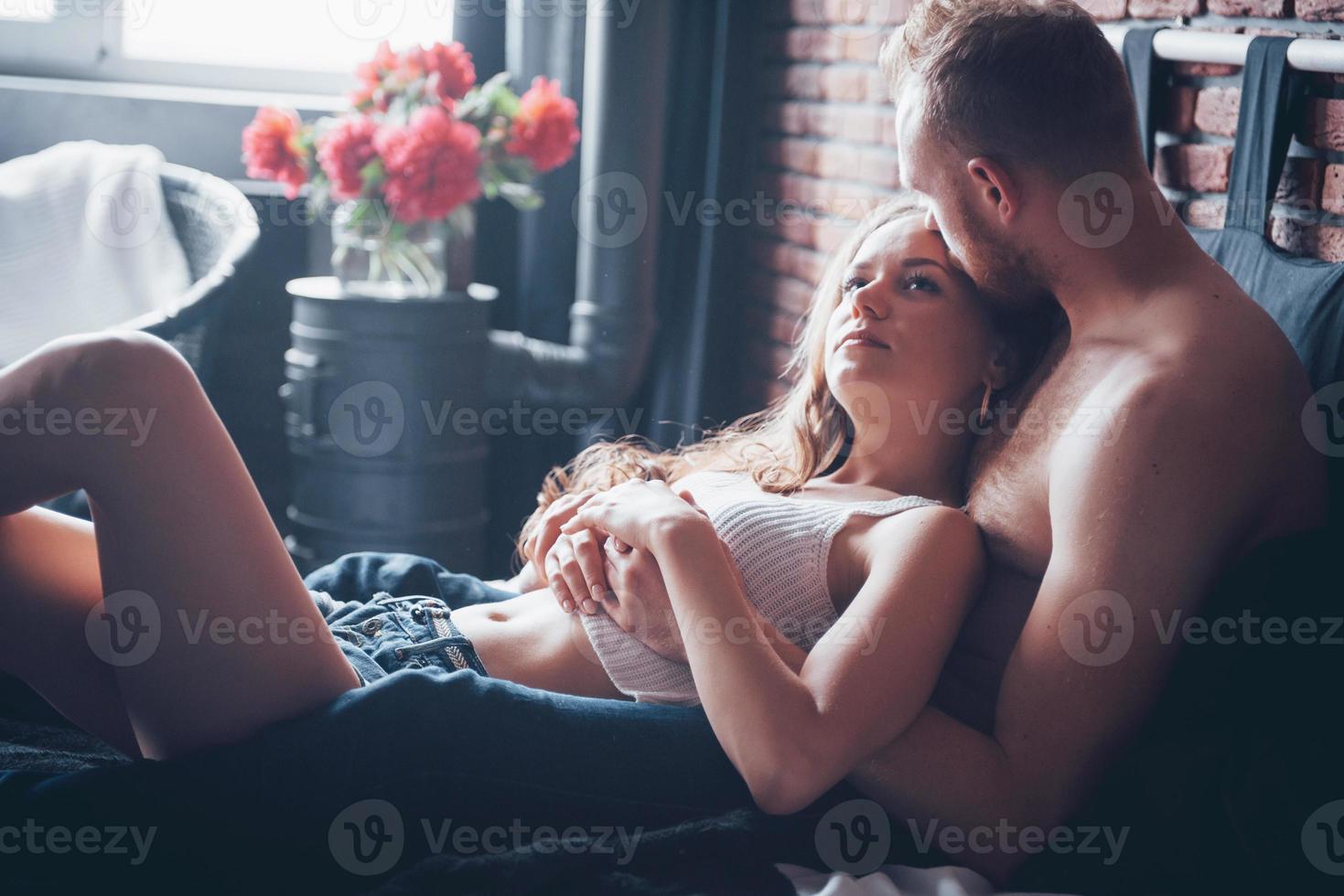 ein Porträt eines glücklichen jungen Paares, das sich in einem gemütlichen Bett entspannt foto