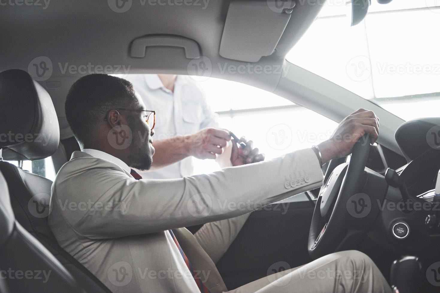 junger schwarzer Geschäftsmann Probefahrt neues Auto. reicher afroamerikanischer Mann foto