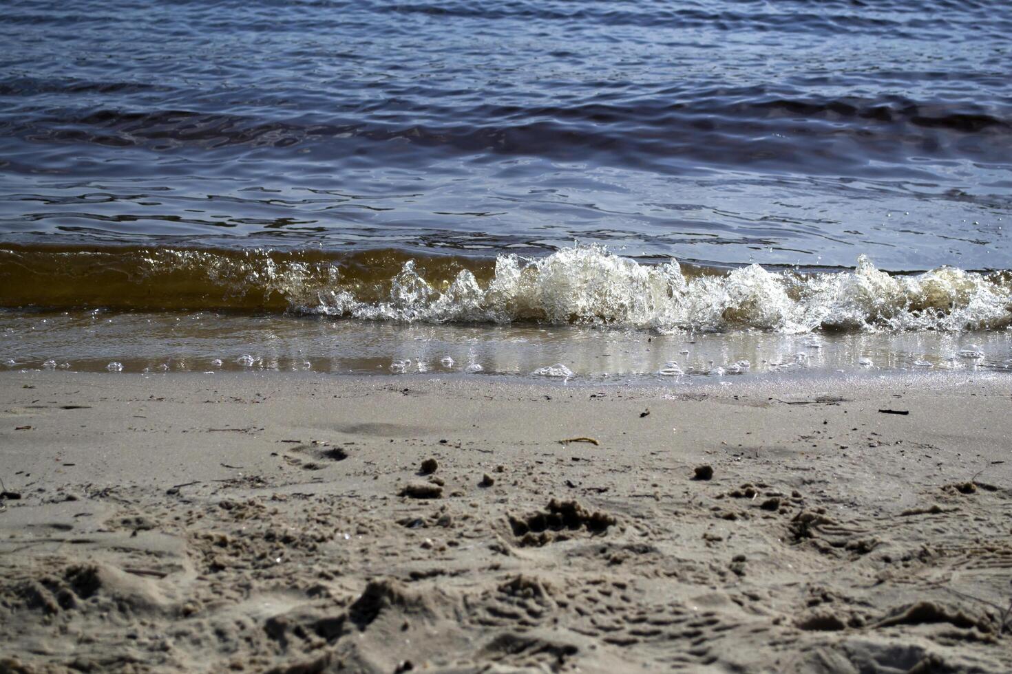 nass Sand und Sanft Wellen auf ein Strand. foto