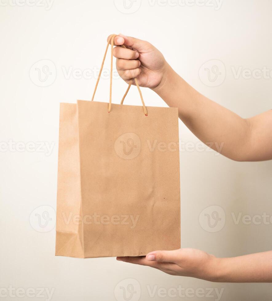 Hand halten ein Einkaufen Papier Tasche gegen ein Weiß isoliert Hintergrund foto