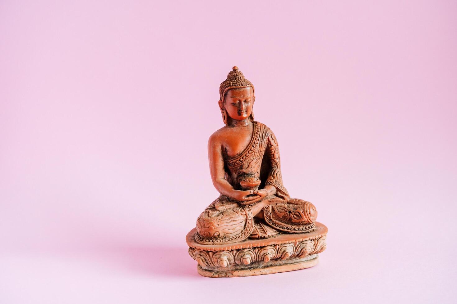Buddha Figur auf ein minimalistisch Rosa Hintergrund. Ohm. bekennen Buddhismus.eins von das drei Welt Religionen. beruhigend Meditationen und Nirwana foto