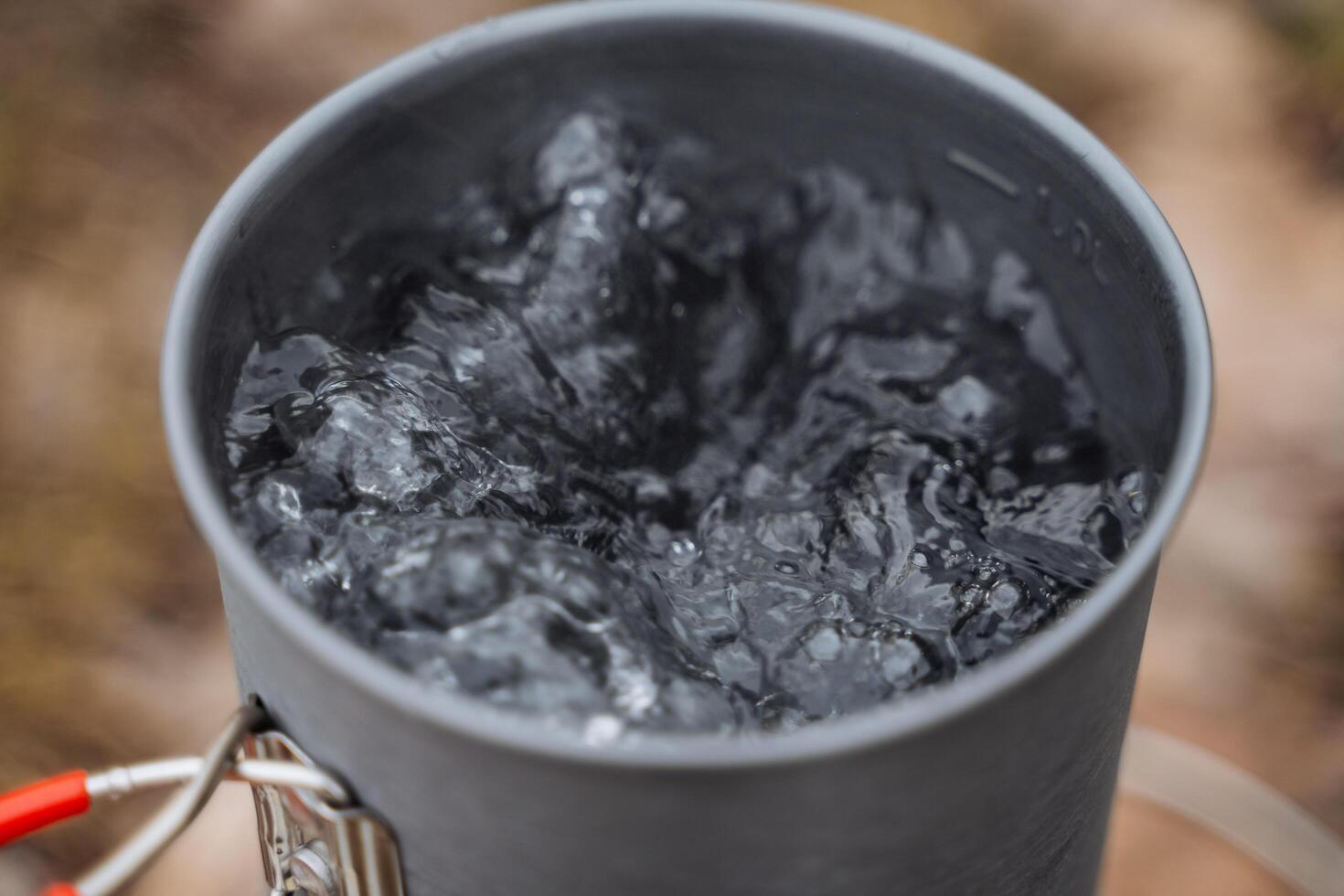 Sieden Wasser im ein Topf, Schuss Nahansicht von Wasser Luftblasen wann erhitzt, Tourist Topf, brauen Tee, Kochen auf ein Wanderung. foto