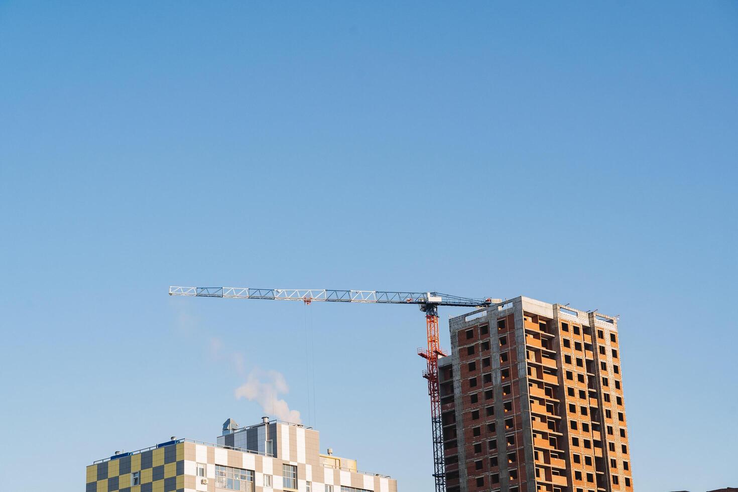 Kran gegen das Blau Himmel. Konstruktion Grundstück, ein Maschine zum Heben schwer Ladungen zu das Höhe von ein mehrstöckig Gebäude. foto