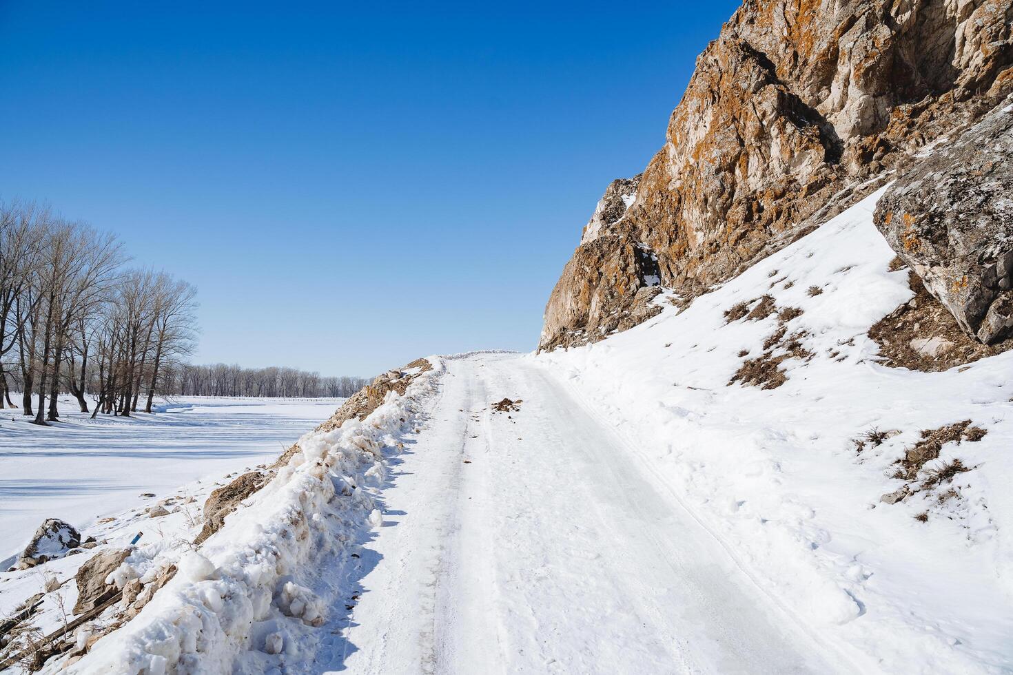 das Straße ist bedeckt mit Schnee Über das Horizont gegen das Hintergrund von ein Blau Himmel. Winter Straße im das Berge. klar Wetter. foto
