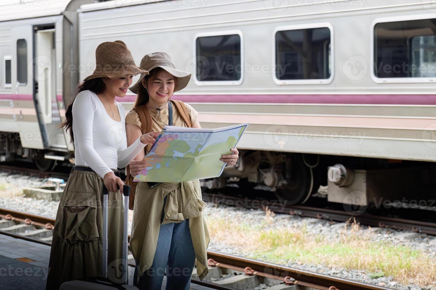 Reise Konzept. Mädchen Freund tragen Hut halten Karte haben Tasche und Gepäck. weiblich Reisender warten Zug beim Zug Bahnhof foto