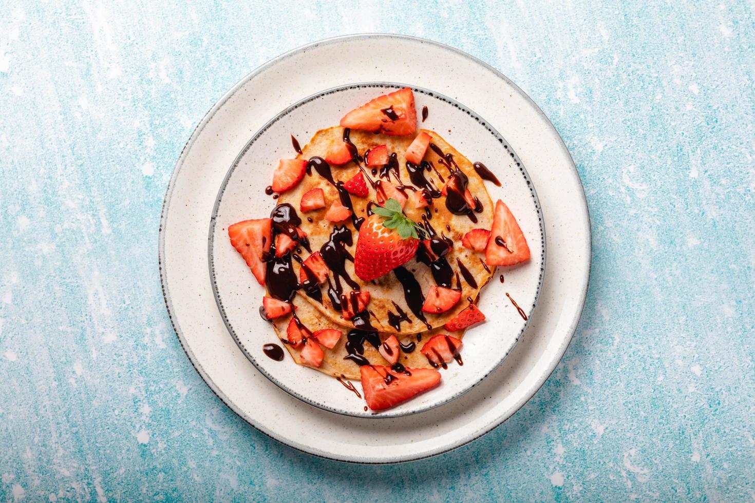 Pfannkuchen mit frischer Erdbeere auf blauem Holzhintergrund foto