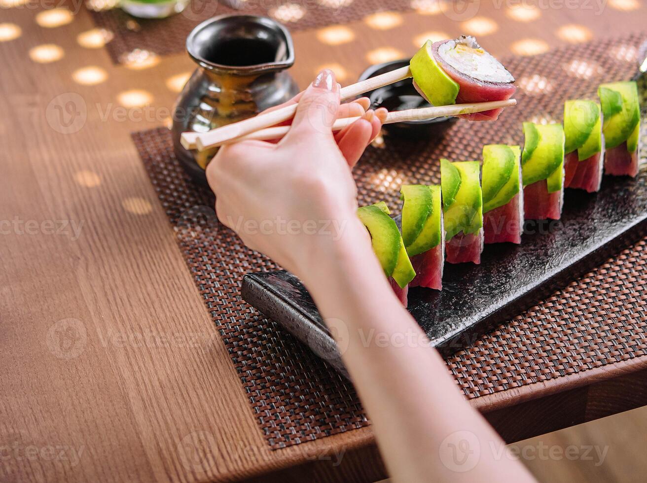 Mädchen Essen Sushi Rollen eingewickelt mit Thunfisch und Avocado foto