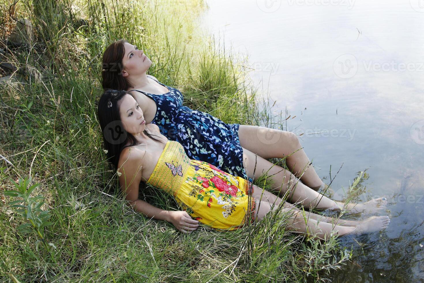 zwei Frauen draußen Fluss Kleider Füße im Wasser foto